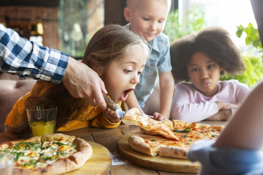 Enfants partageant une pizza, illustrant l’offre de snacking en camping.