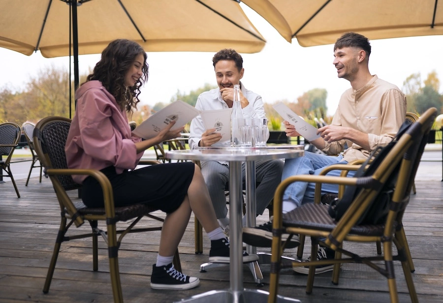 Groupe de vacanciers en terrasse de camping consultant le menu d'un point de snacking