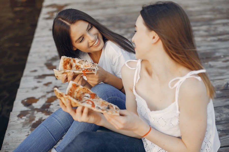 Vacanciers dégustant des parts de pizza en extérieur lors d'une soirée en camping